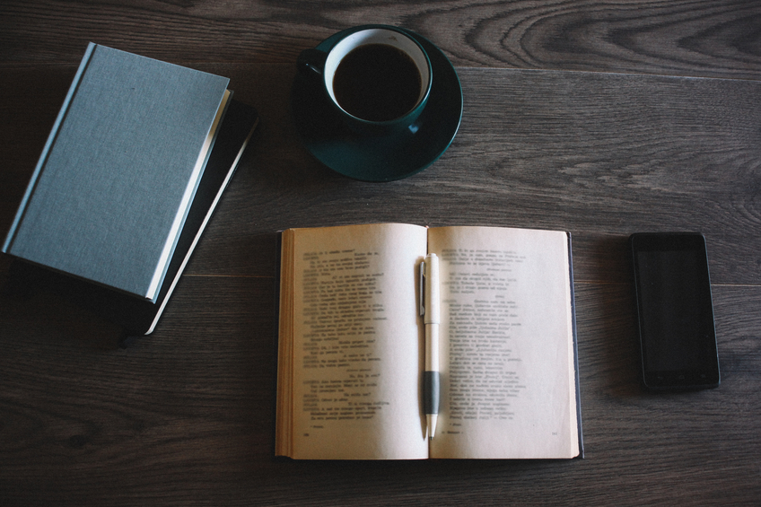 Books, coffee and a smartphone on the wooden background