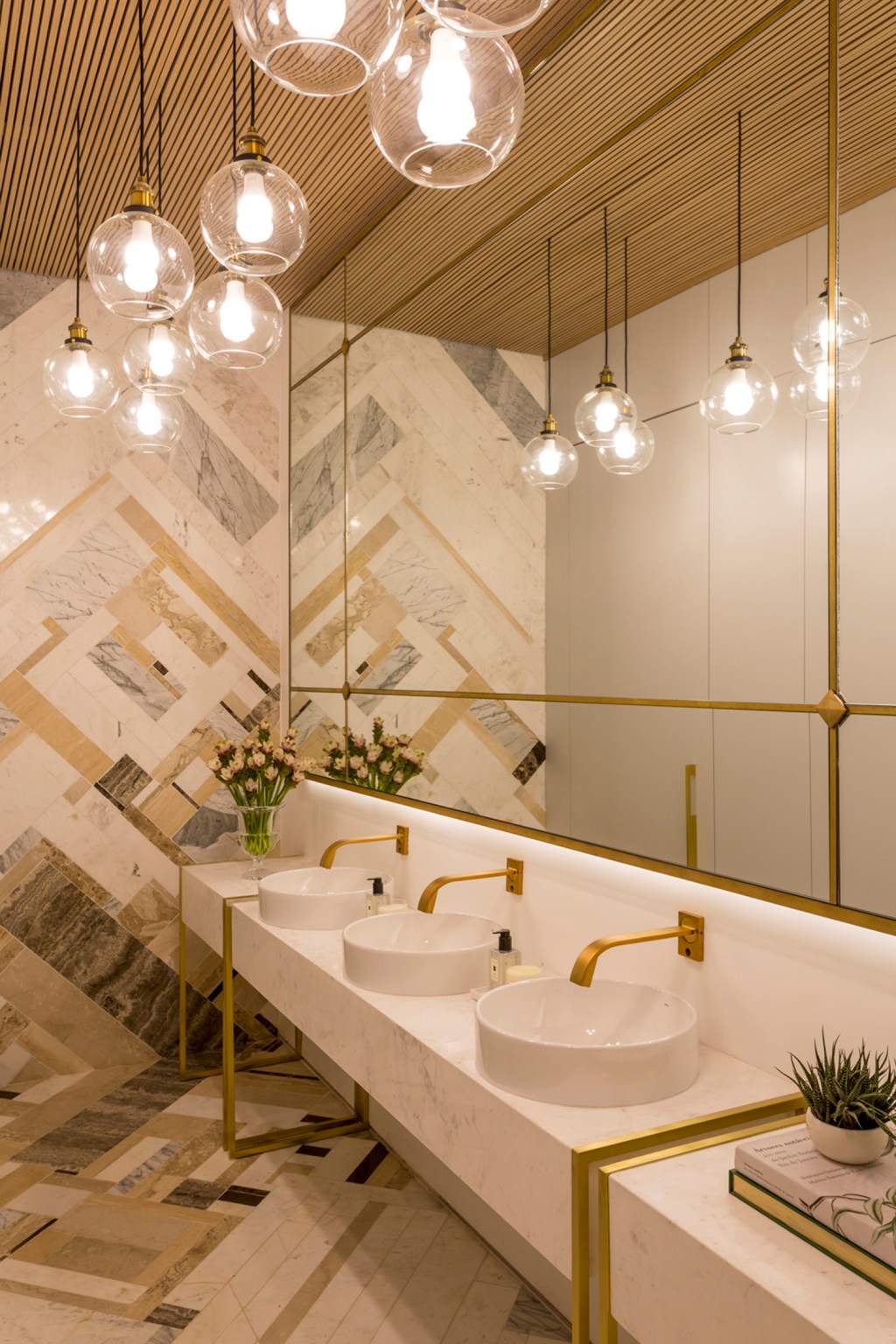 Aparas de mármore revestem parede e piso de banheiro na CASACOR SP